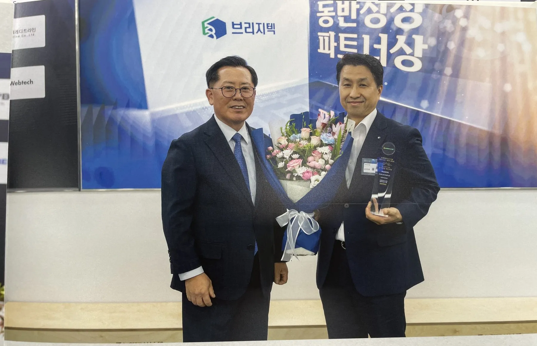 농협정보시스템 관계자와 함께 꽃다발과 상패를 들고 기념 촬영하는 윤종우 이사
