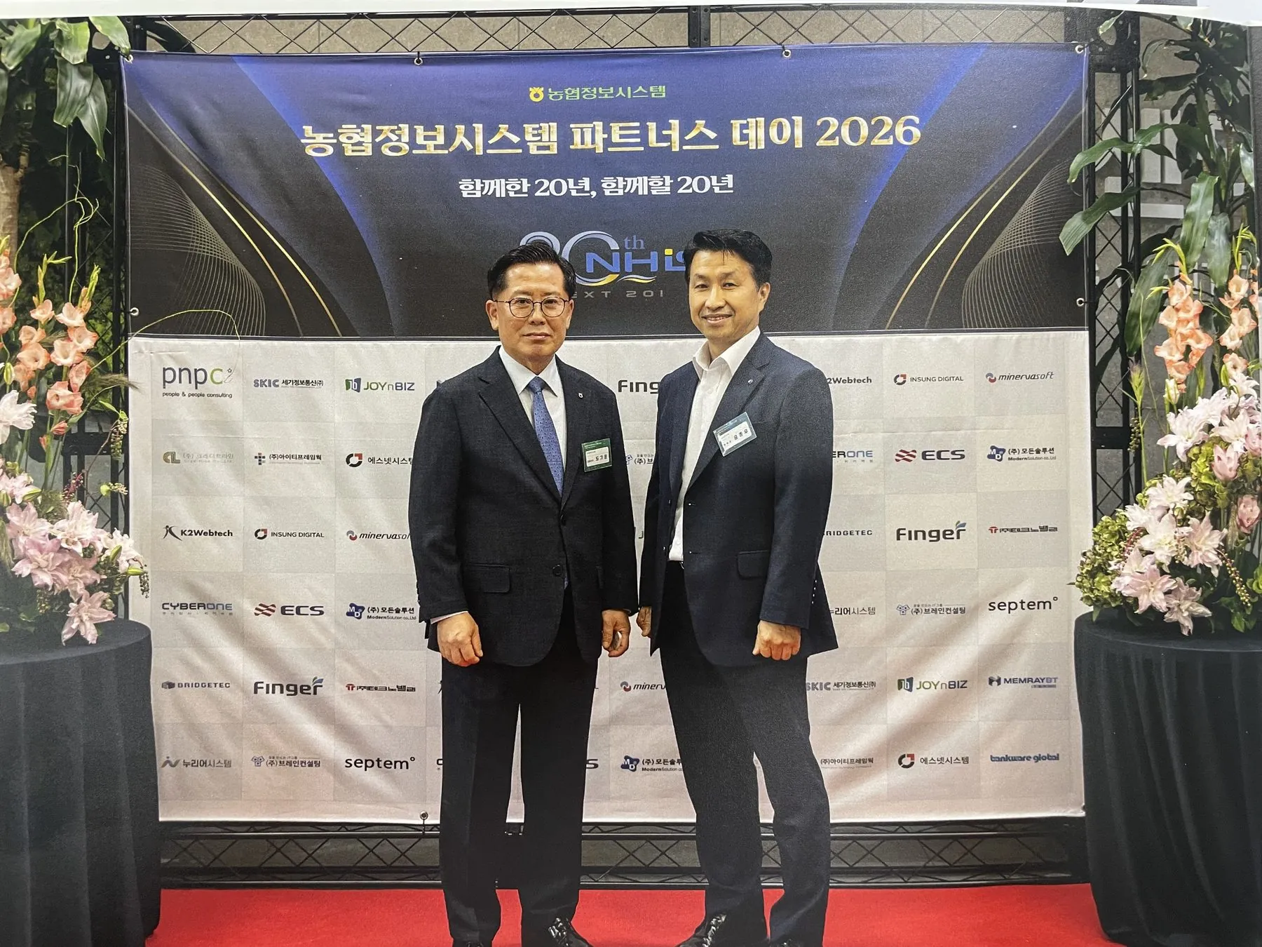 농협정보시스템 파트너스 데이 2026 포토월 앞에서 관계자와 함께 선 윤종우 이사